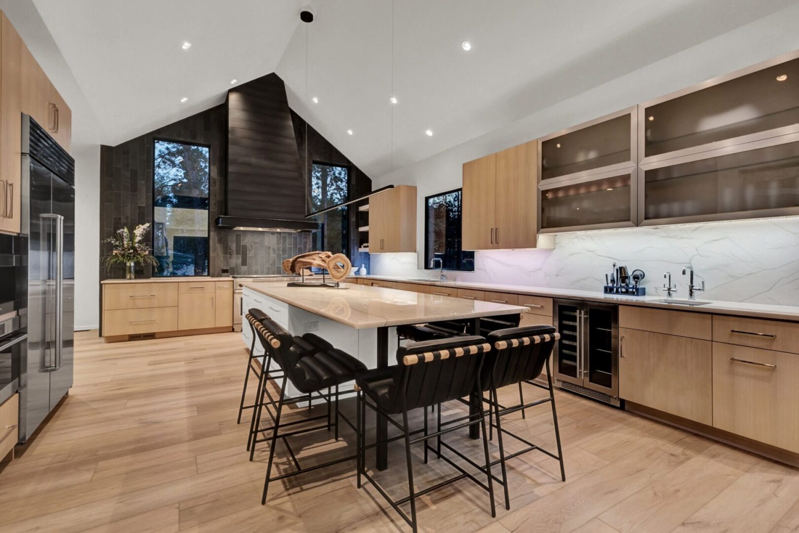 modern kitchen with black range hood and siding accent wall with blonde cabinetry