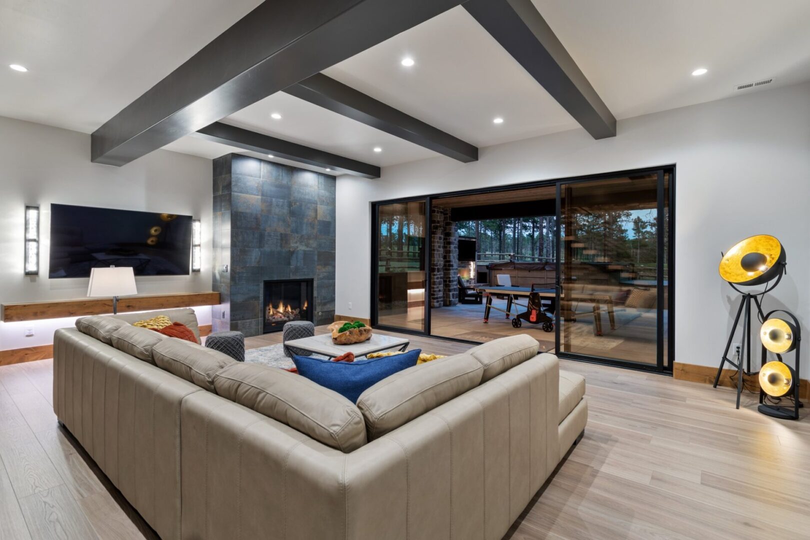 walkout lower level family room with ceiling beams, linear fireplace and large sliding pocket doors