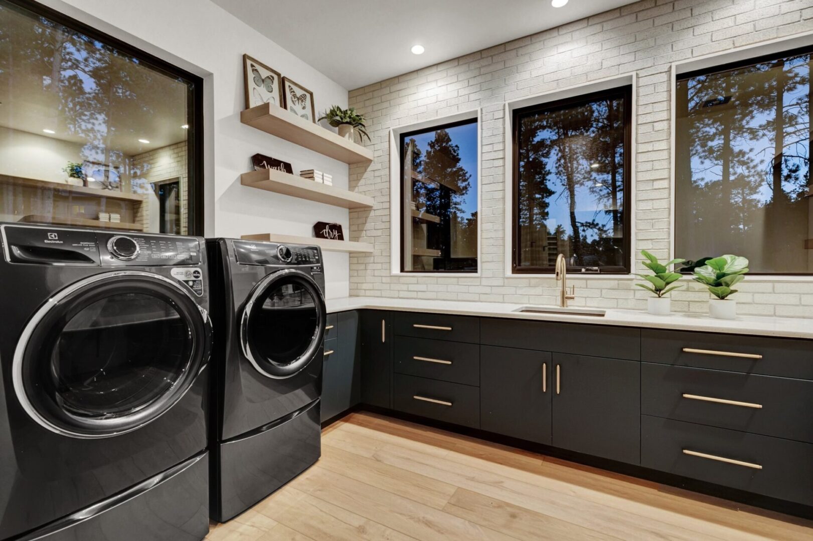 modern laundry room with black cabinets and white tiled walls
