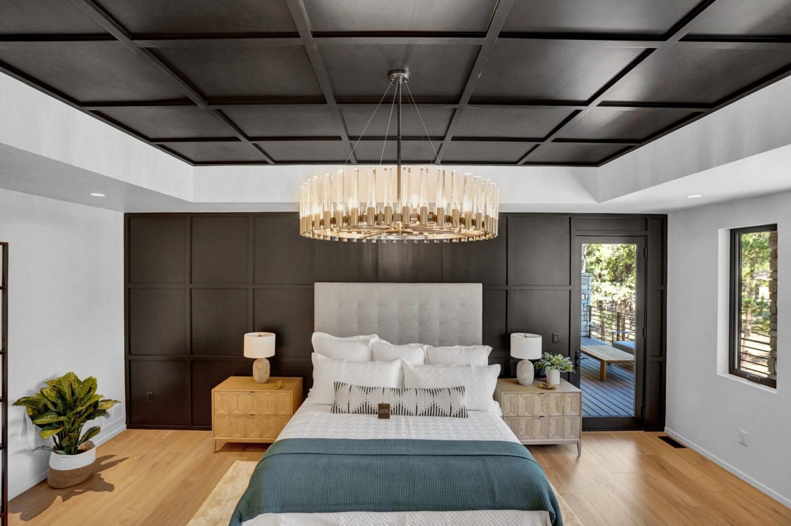 Modern primary bedroom with black accent panel moulding wall and ceiling with large upholstered bed and crystal chandelier
