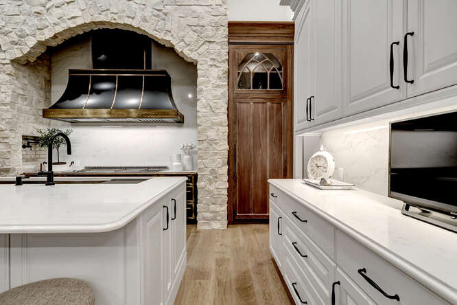 Kitchen with white cabinets and accent custom wood cabinets and french metal black range hood