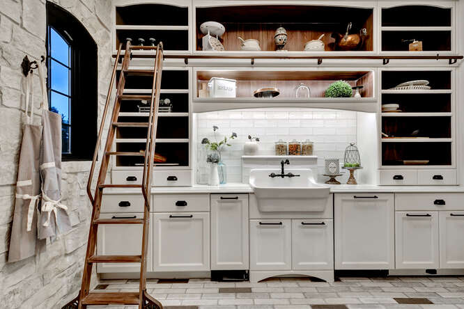 Butler's pantry with white cabinets and built-in sliding ladder and apron front sink