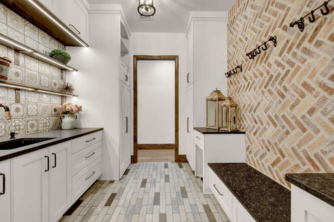 Brick accent wall in laundry room with built-in bench and shelving