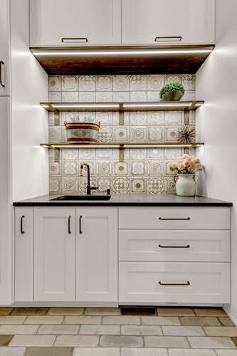 French Country laundry room with built in shelves and decorative tile backsplash for laundry sink