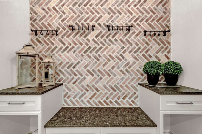 Brick accent wall in laundry room with built-in bench and shelving