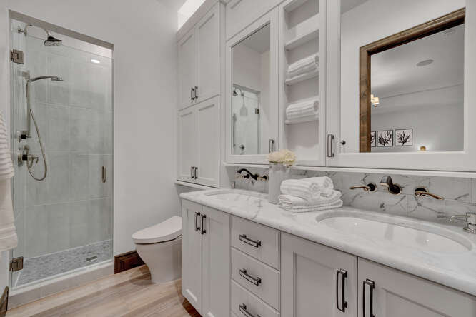 Bathroom with white vanity cabinets and wall mounted faucets