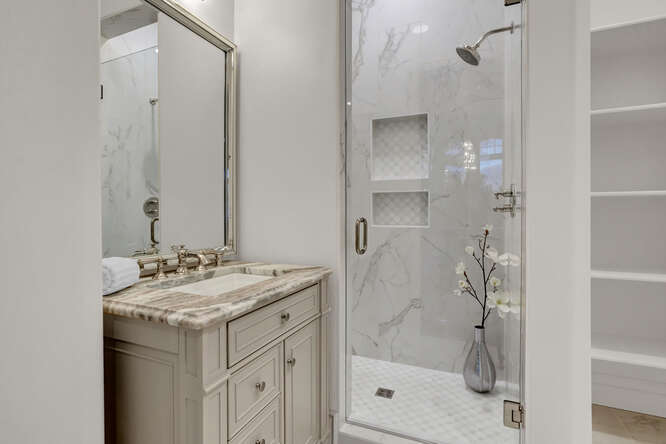 Bathroom with light gray vanity cabinets and shower with glass door