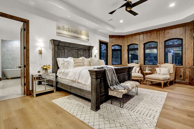 Primary Suite Bedroom with large black bed and wood panel accent window wall