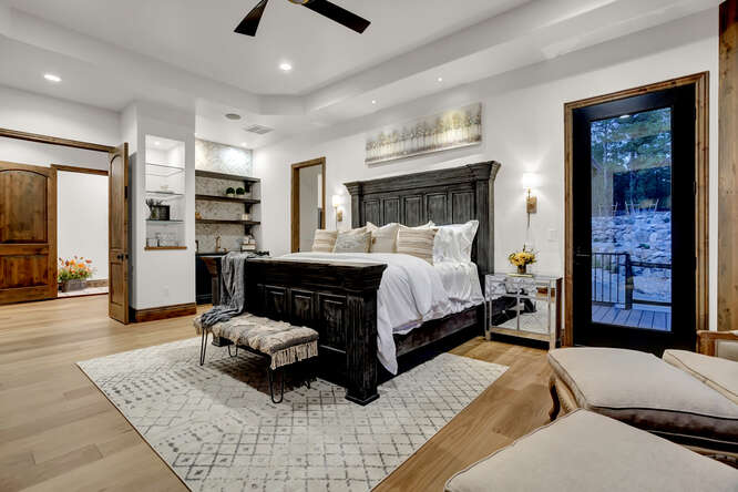 Primary Suite Bedroom with large black bed and coffee bar in the background