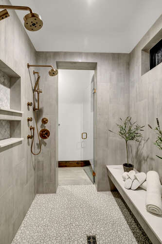 Primary Bathroom Spa Shower with brass shower heads and fixtures and built-in bench