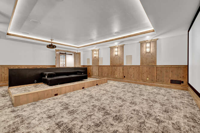 Home theater with wood panel wall and movie screen and large black leather seating