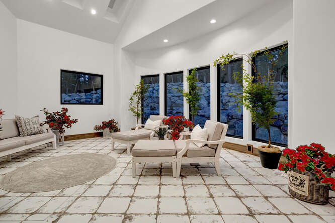 Greenhouse sitting room with tall windows and patio furniture with plants