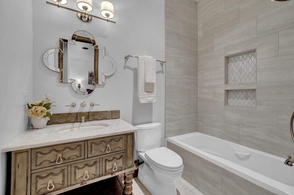 French country bathroom with tub, medium stain sink vanity cabinet with a toilet and septic system