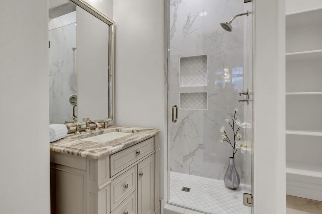Bathroom with full wall tile shower. Vanity sink cabinet with natural stone counters.