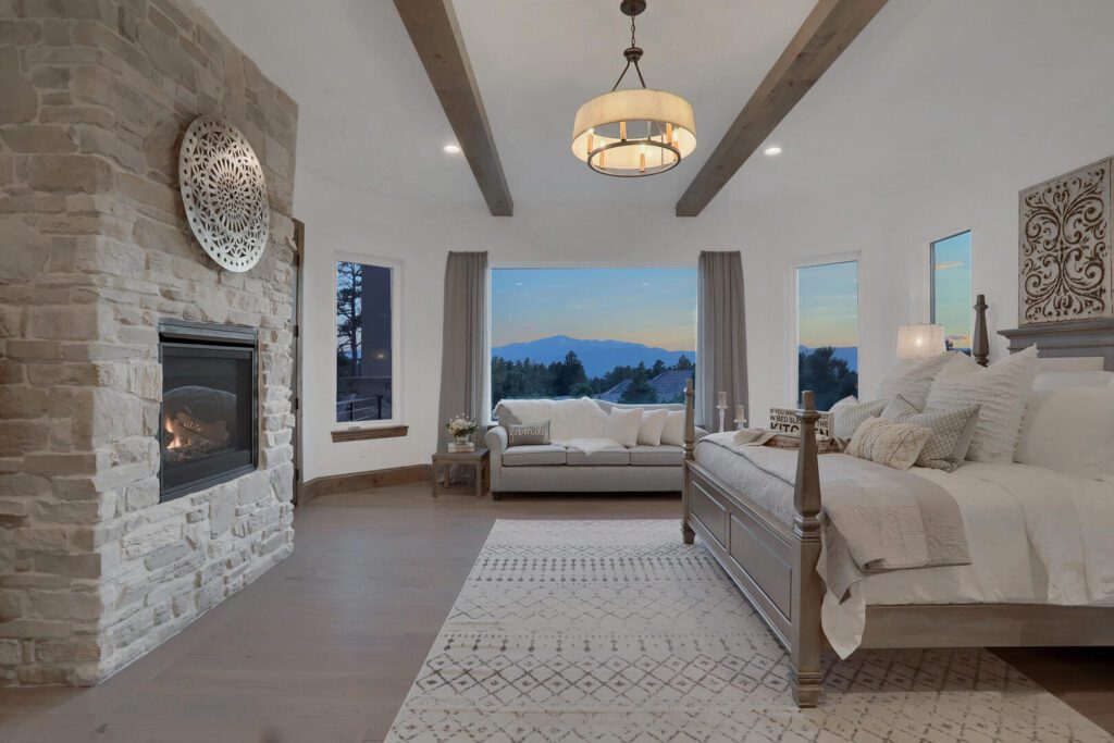 Countryside Craftsman custom home primary suite with fireplace and wood beam ceiling